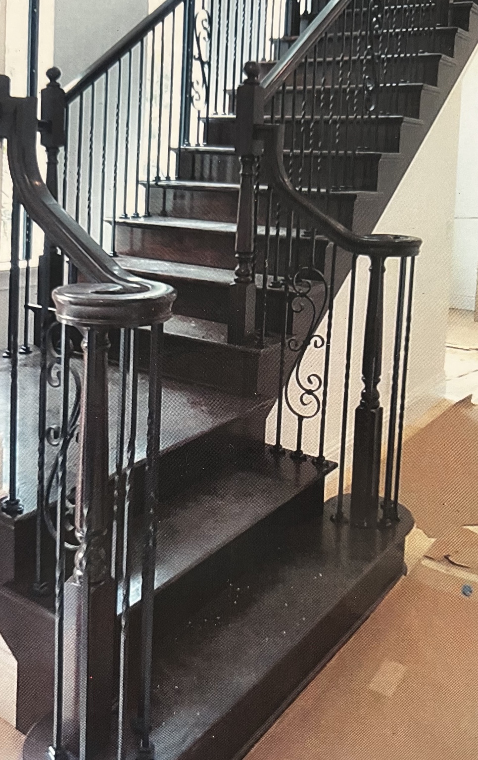 Dark wood staircase with sweeping handrails and decorative iron balusters