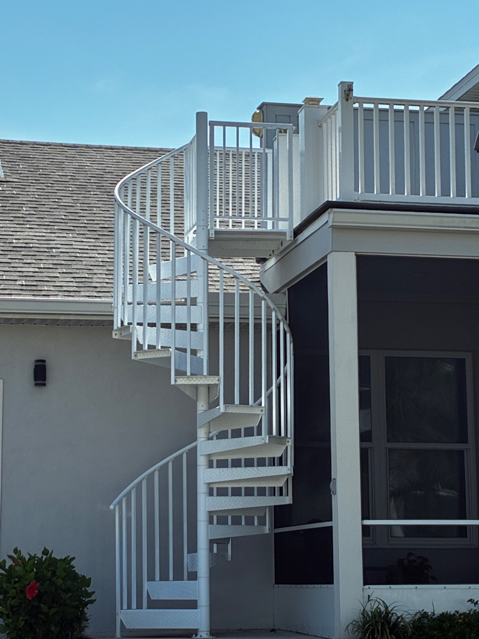 White outdoor spiral staircase connecting the ground level with a rooftop deck