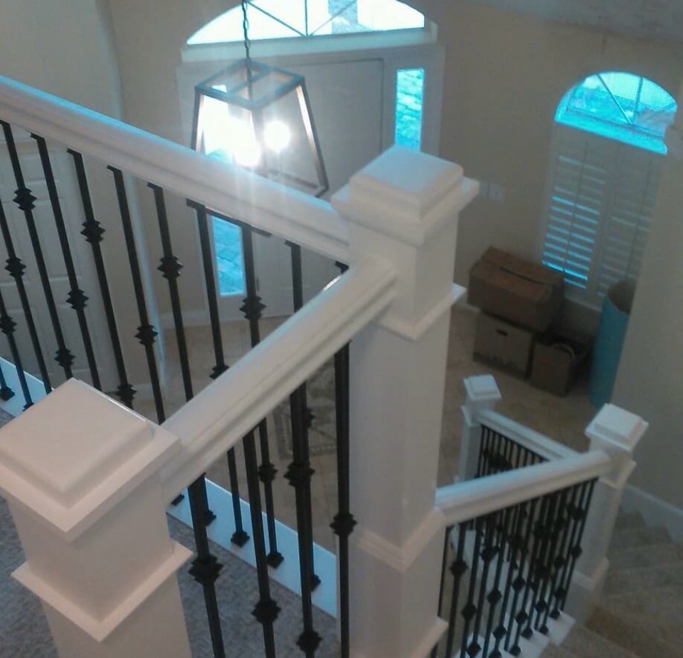 White stair railings and newel posts with decorative black iron balusters
